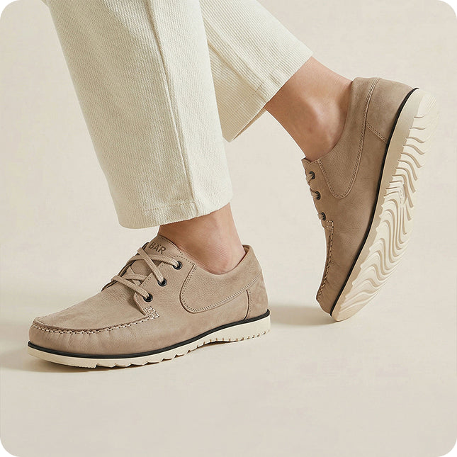 Beige casual shoes worn with light-colored pants on a neutral background