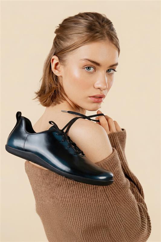 Woman holding a black shoe against a beige background