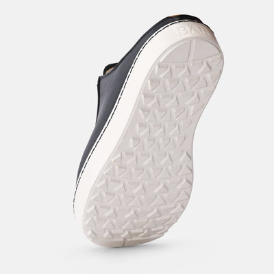 Close-up of a shoe sole with white tread pattern on a light gray background