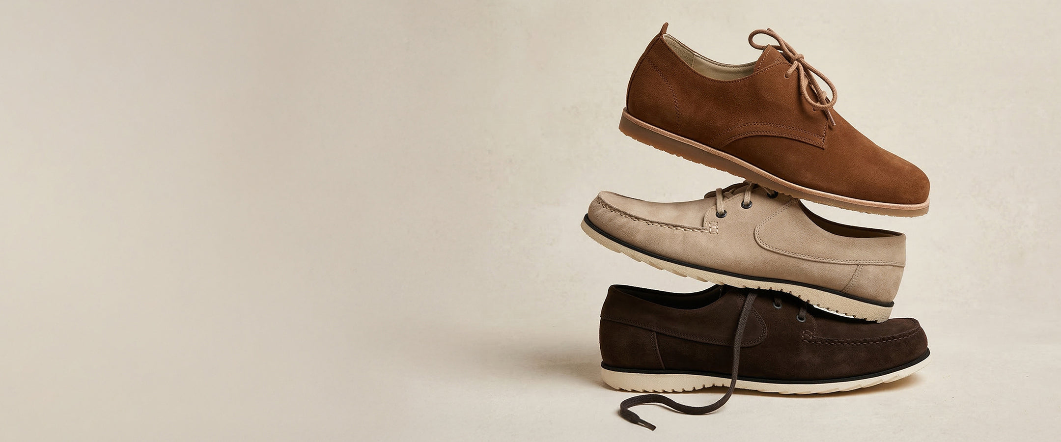 Three pairs of shoes stacked on a beige background